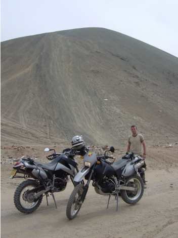 Two motorcycles below a steep volcanic slope